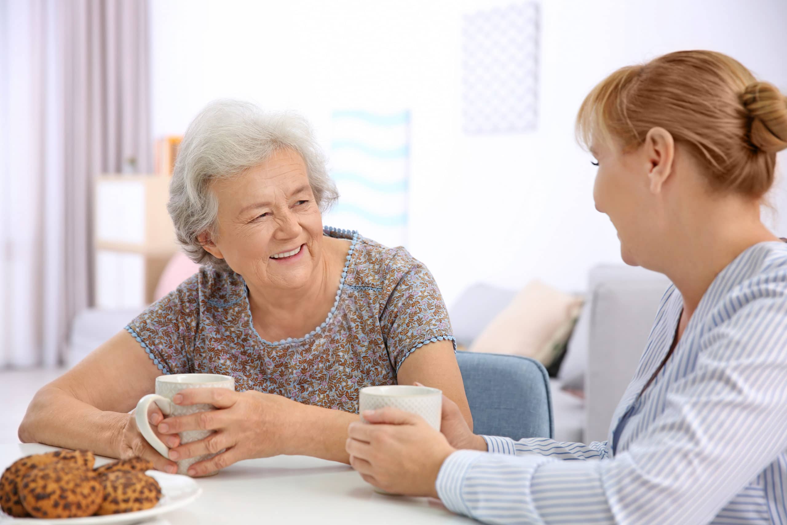 A compassionate caregiver sharing a warm moment with an older woman at home
